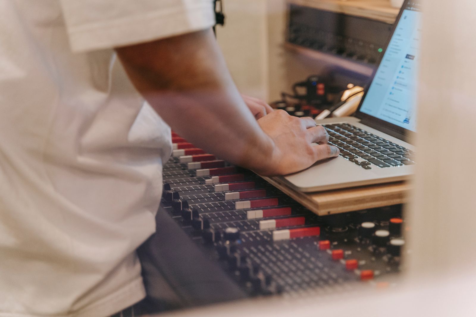 Gros plan sur des boutons, des faders et des touches d'un clavier de studio posé sur un bureau sombre