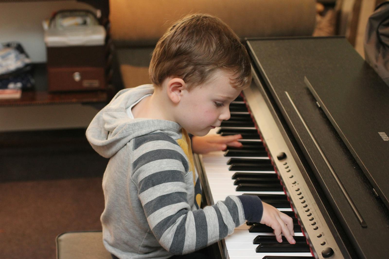 Jeune enfant assis devant un piano numérique à la maison