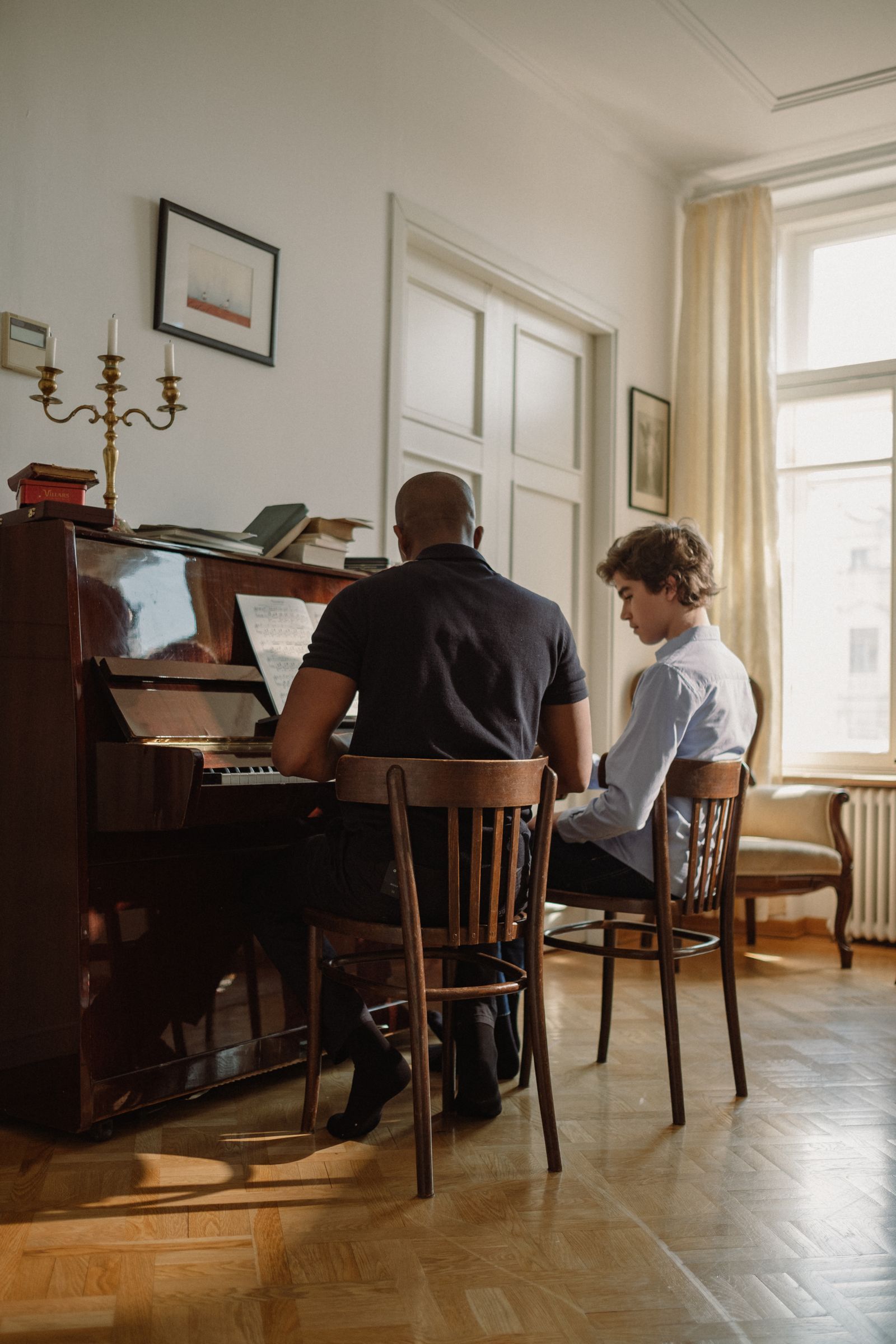 Professeur et élève assis devant un piano droit, cours de piano en présentiel
