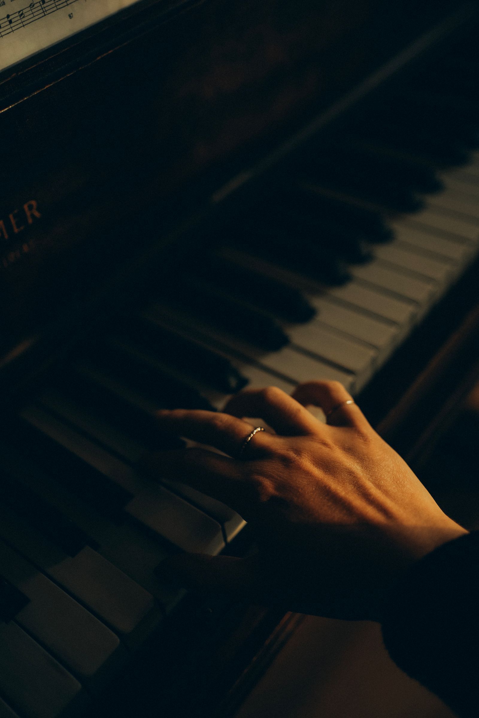 Main de pianiste posée sur les touches d'un piano, en lumière tamisée
