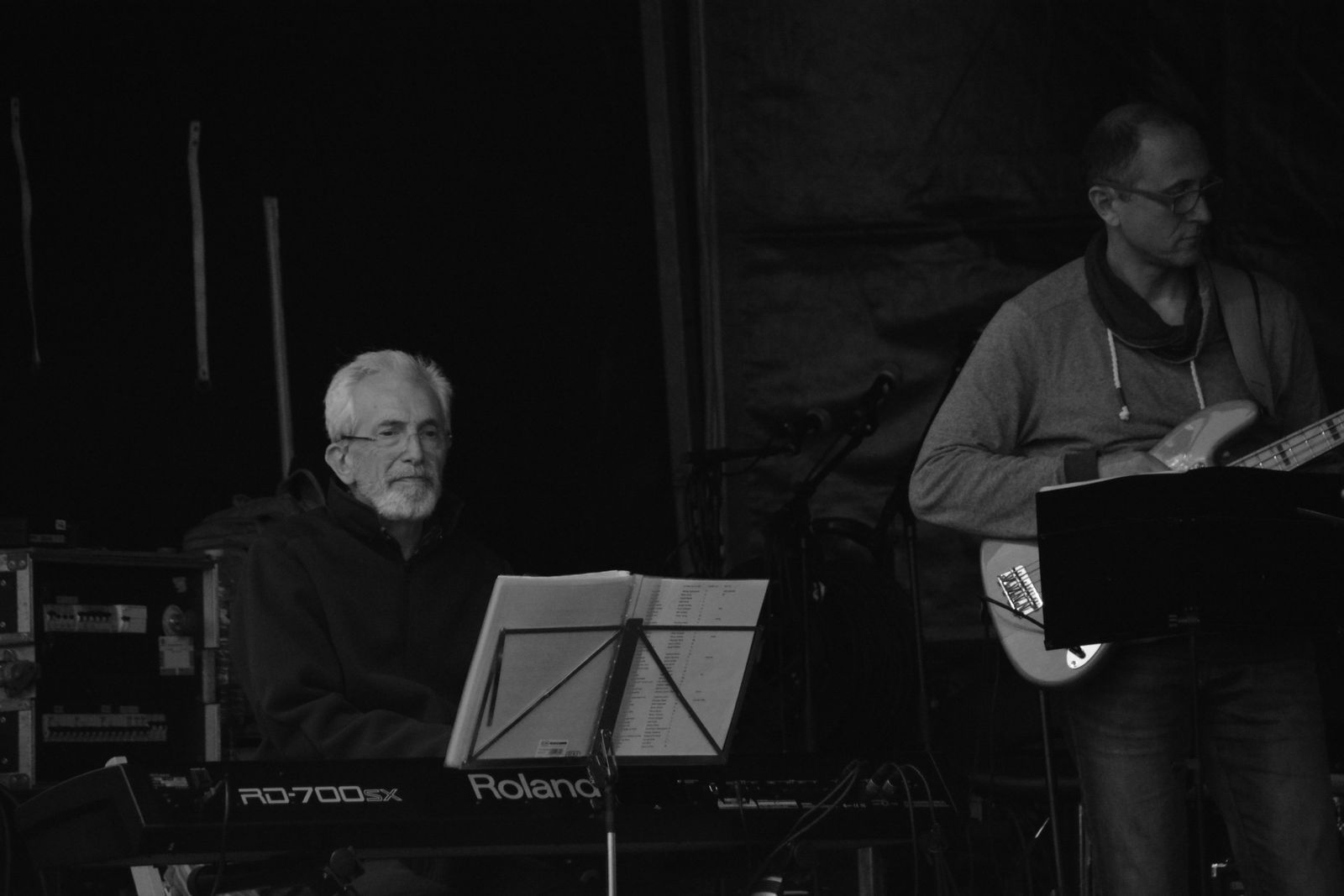 Musicien jouant du clavier numérique sur scène en extérieur, de nuit, aux côtés d'un bassiste