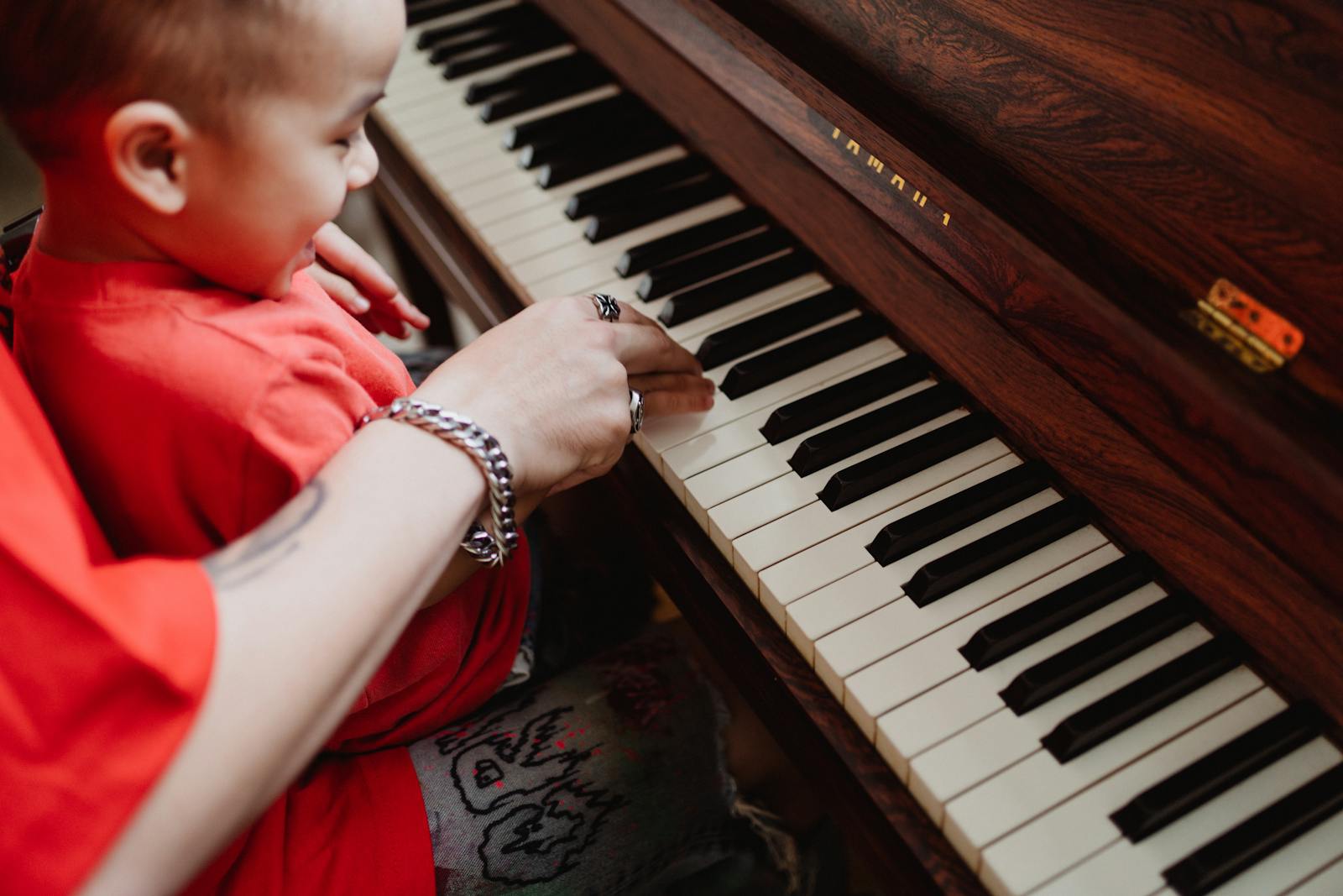 Un parent accompagnant son jeune enfant au piano à la maison
