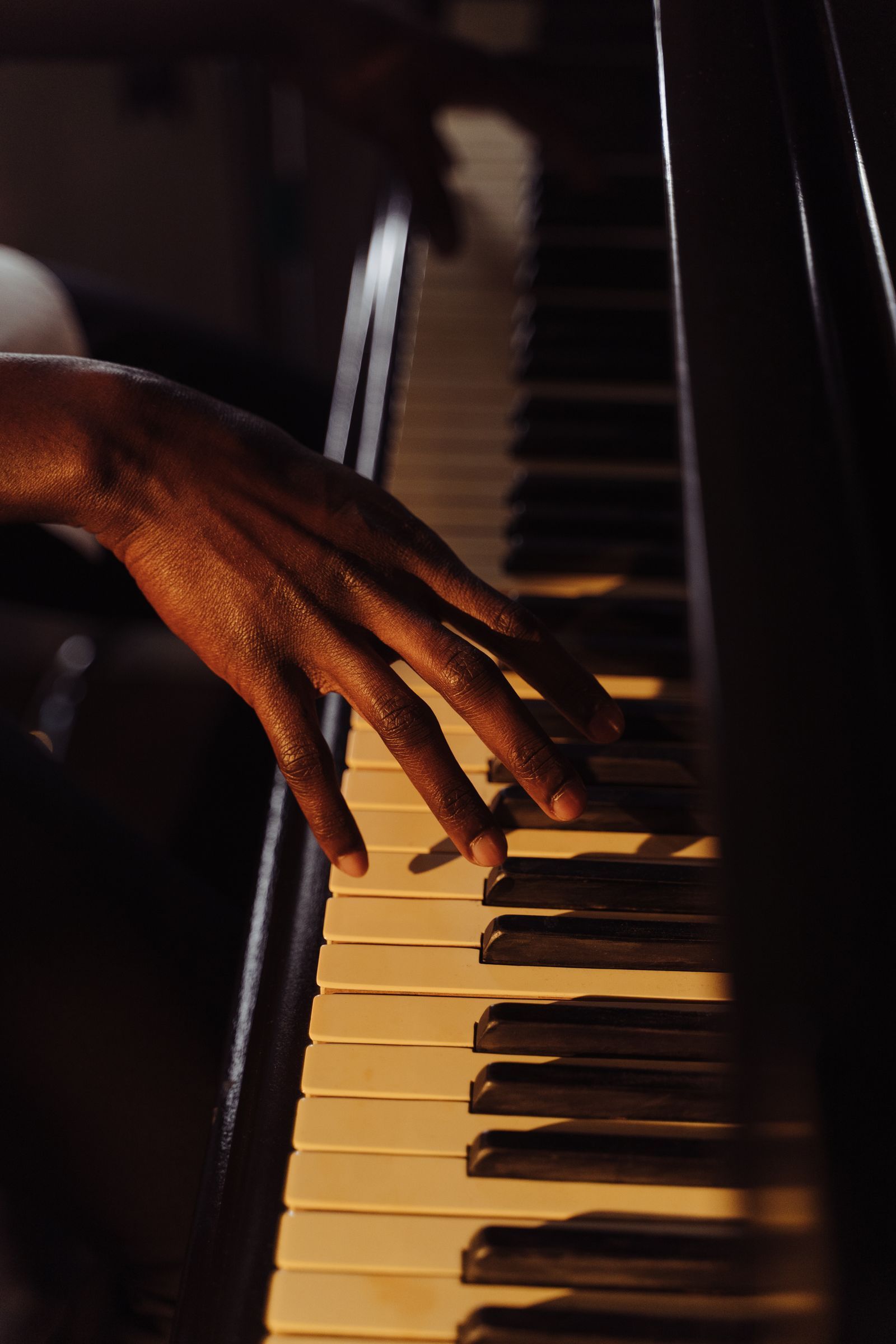 Main posée sur les touches d'un piano, éclairée par une lumière chaude