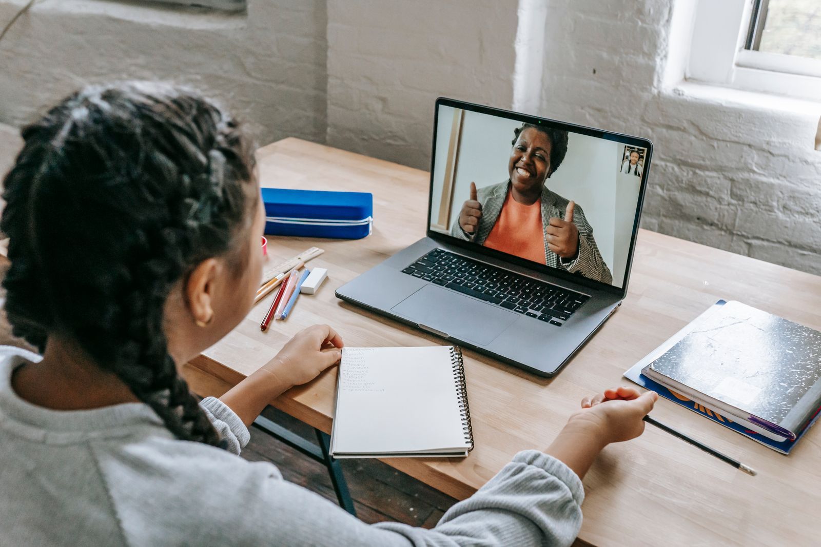 Jeune fille en cours de piano par visioconférence, professeure souriante à l'écran du laptop