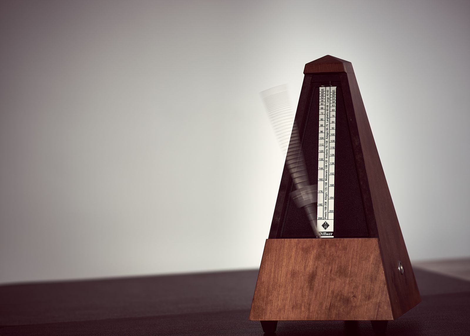 Métronome mécanique en bois posé sur une table, utilisé pour le travail du rythme au piano