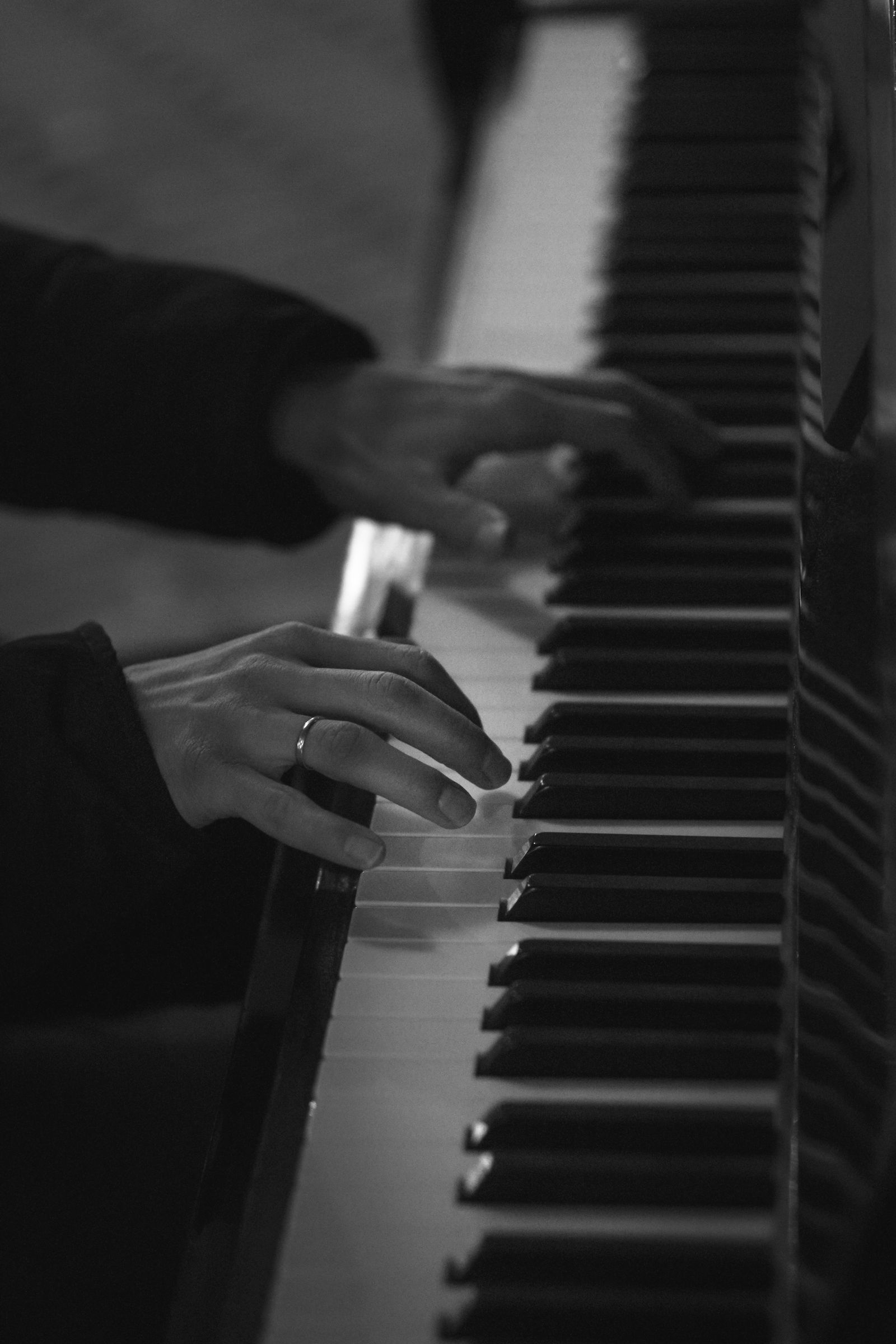 Gros plan sur les touches blanches et noires d'un piano en noir et blanc, avec une main qui frappe le clavier