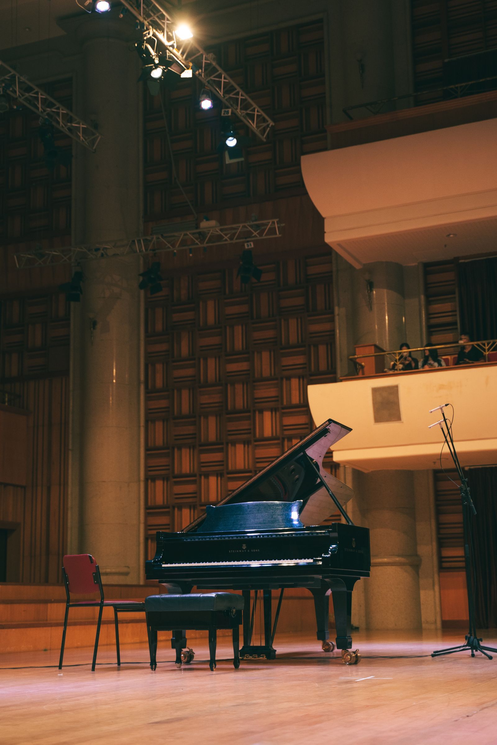 Piano à queue noir installé sur la scène éclairée d'une salle de concert