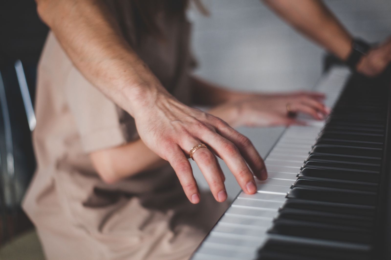Mains posées sur les touches lestées d'un piano numérique