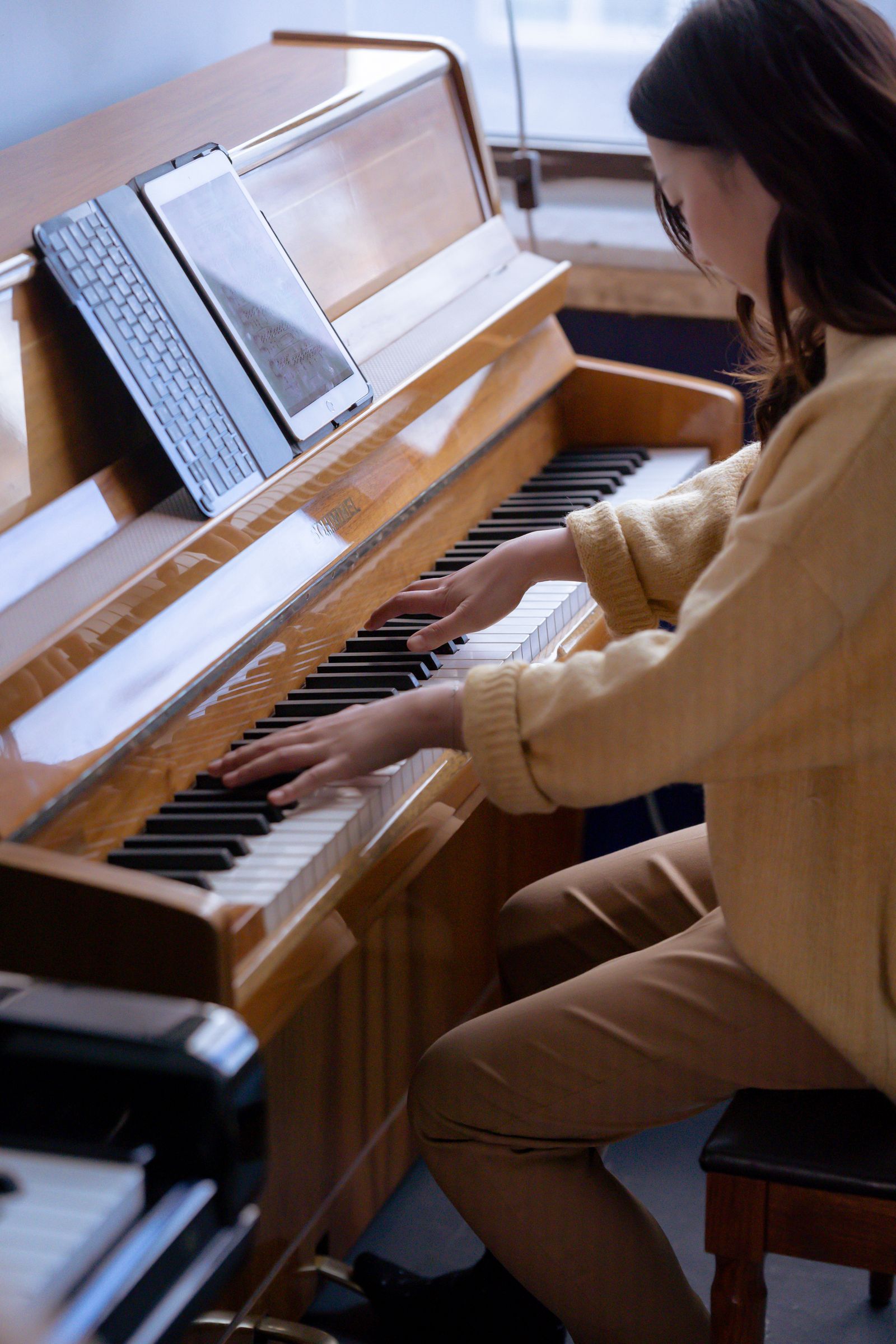 Femme jouant du piano avec une tablette posée sur le pupitre