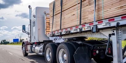 A flatbed truck carrying banded lumber on the highway