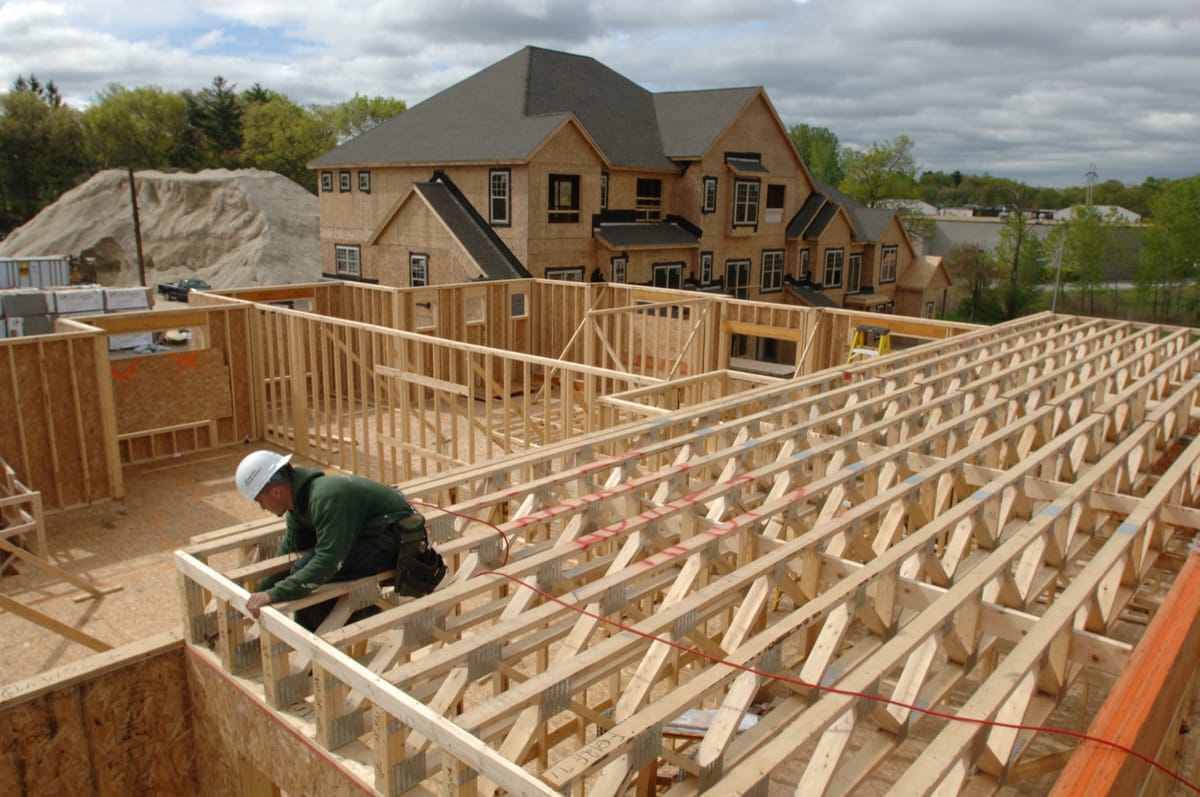 A carpenter working on the timber frame of a house under construction