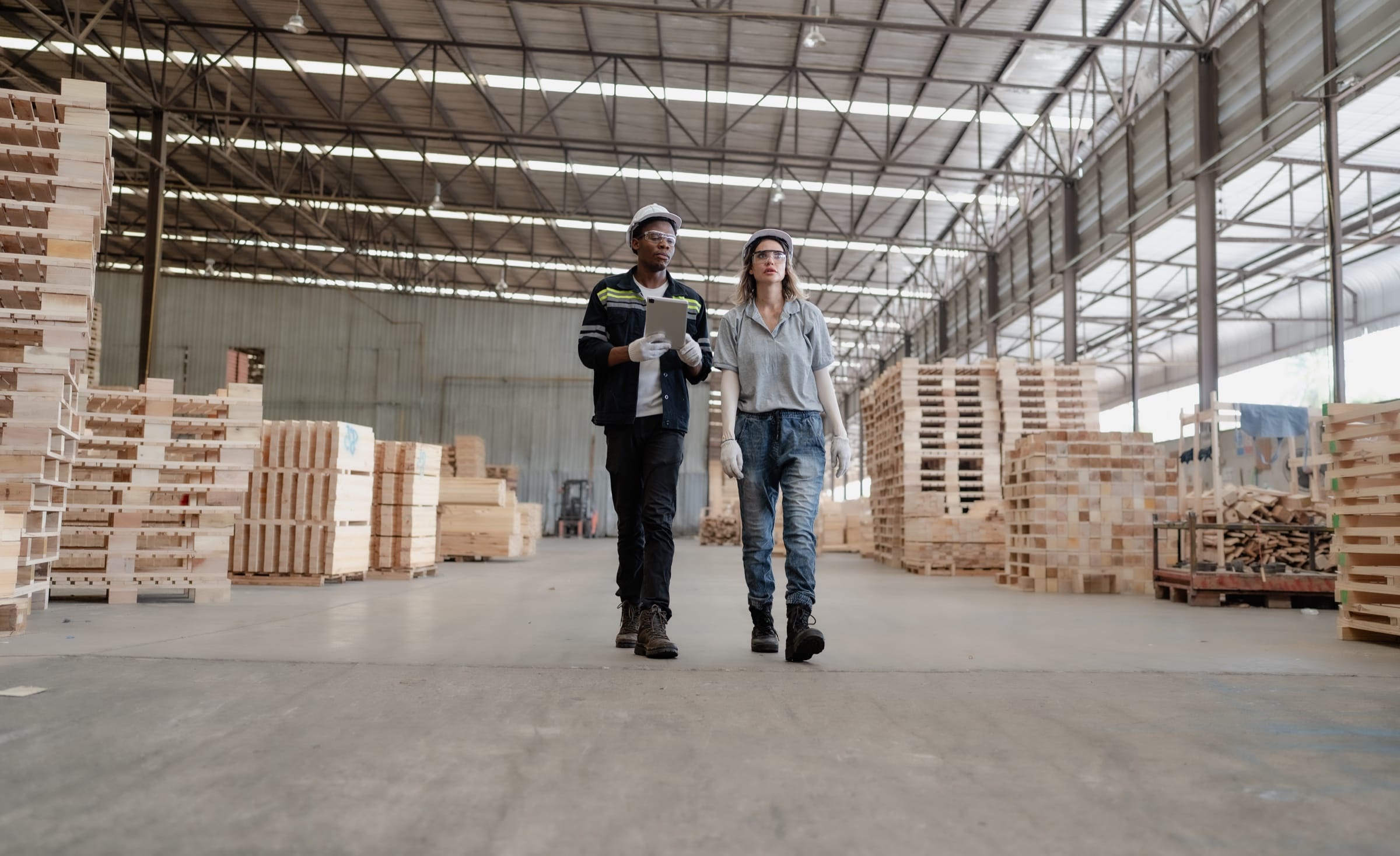 Two operations professionals walking through a lumber warehouse