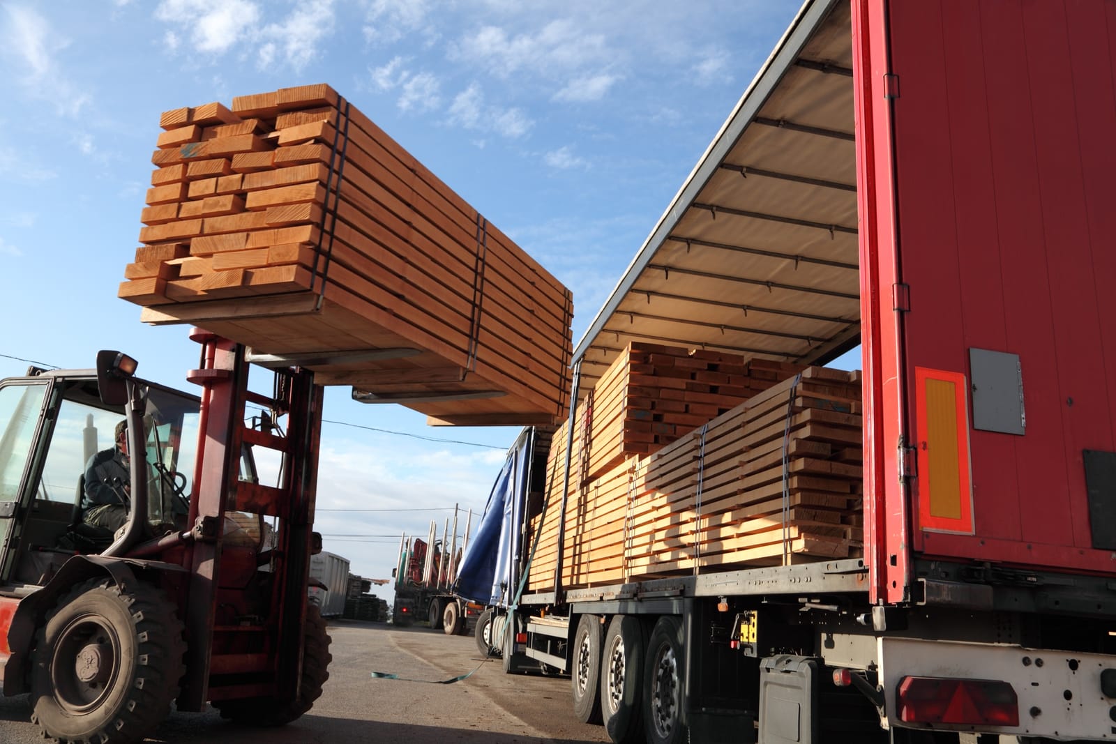 A forklift loading lumber into a delivery truck