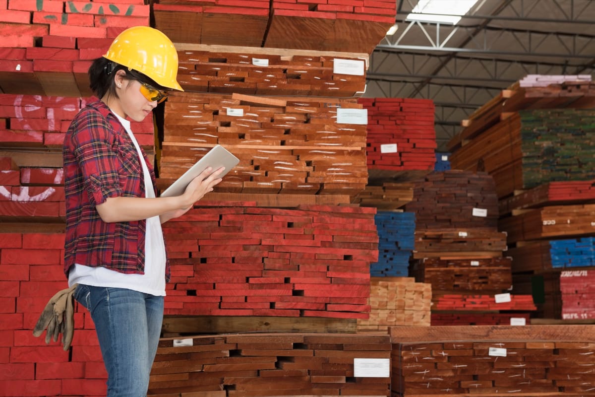 A buyer checking stacked lumber inventory in a warehouse