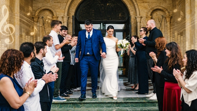 Ein fröhliches Hochzeitspaar welches von klatschenden Gästen umgeben ist.