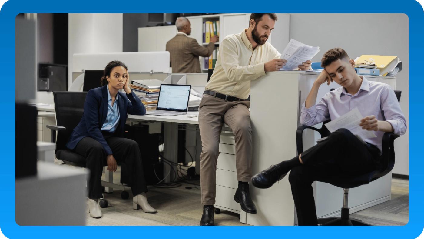 Office staff review paper files while working at separate desks.