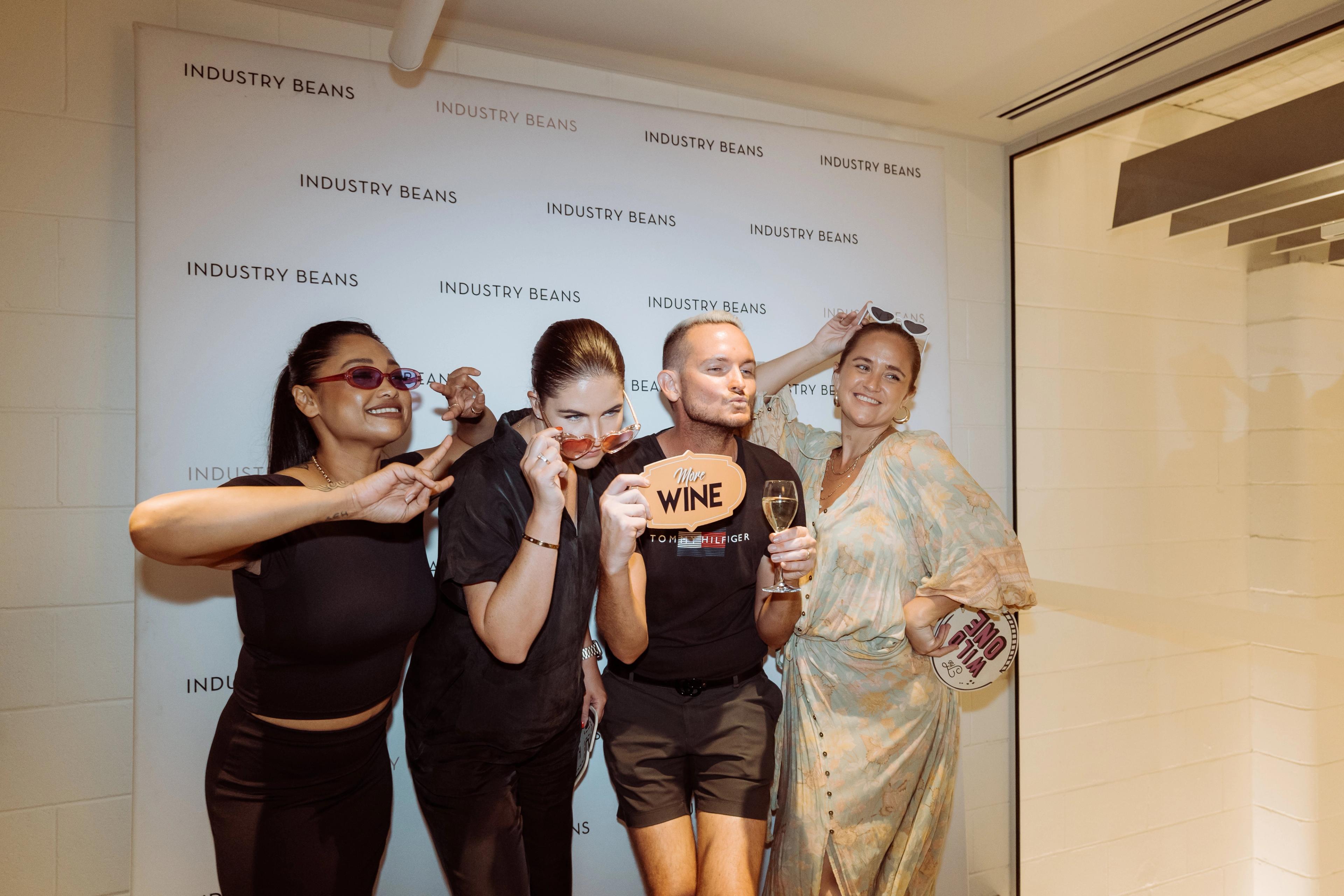 Guests posing with photo props in front of the Industry Beans media wall at the Newstead brand activation in Brisbane.