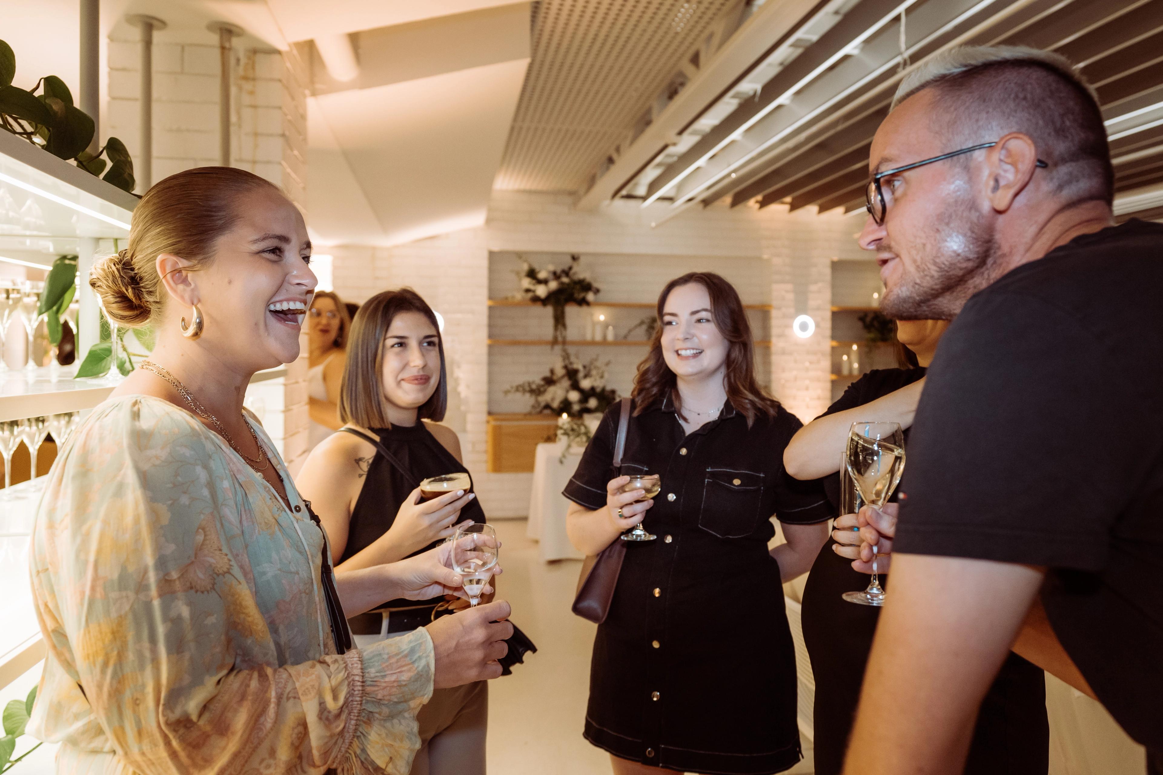 Guests mingling over drinks at Industry Beans Newstead, with warm lighting, floral styling and candlelit event tables in the background.