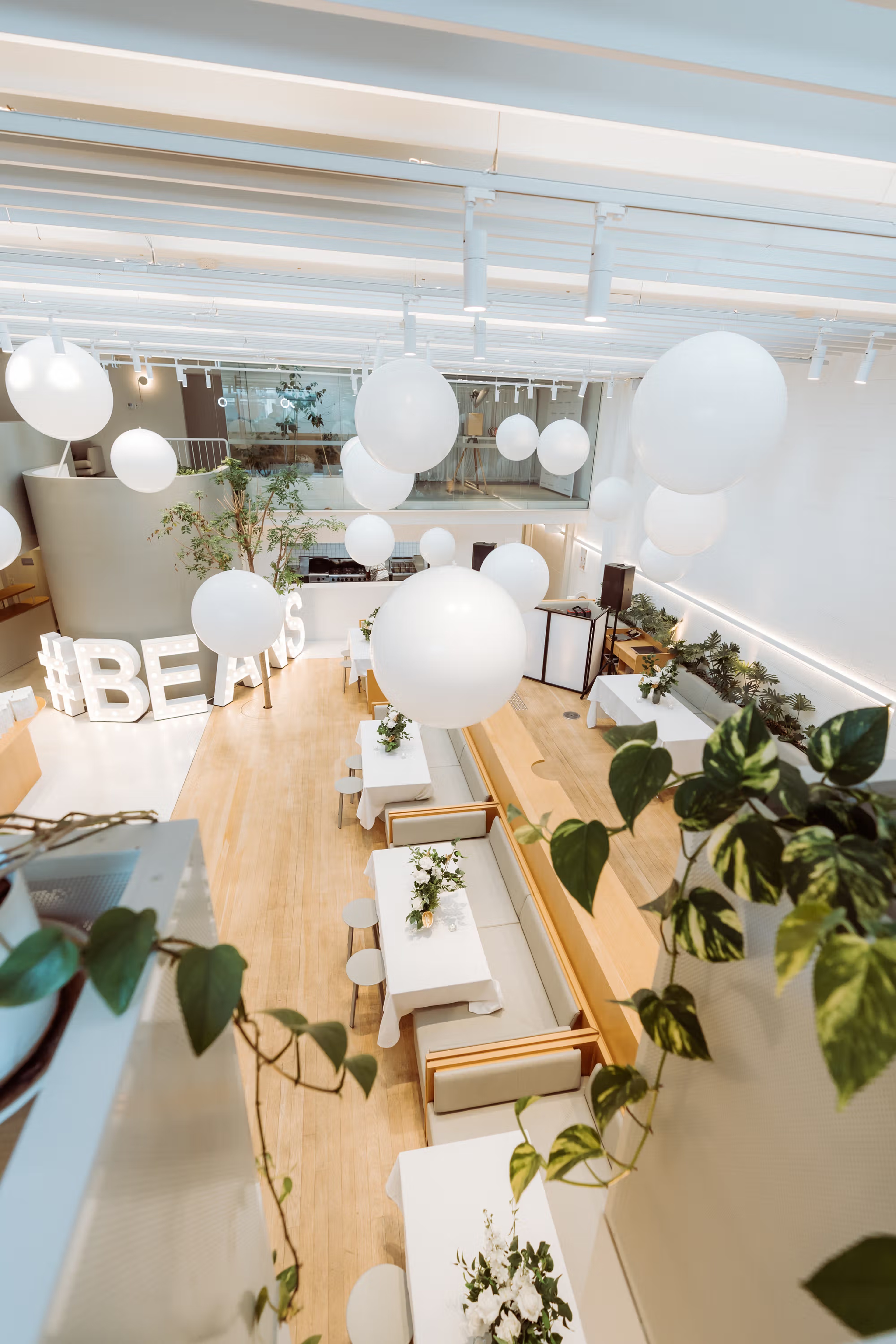 Overhead view of Industry Beans Newstead transformed for a Brisbane brand activation with white balloon installations, styled tables and greenery.