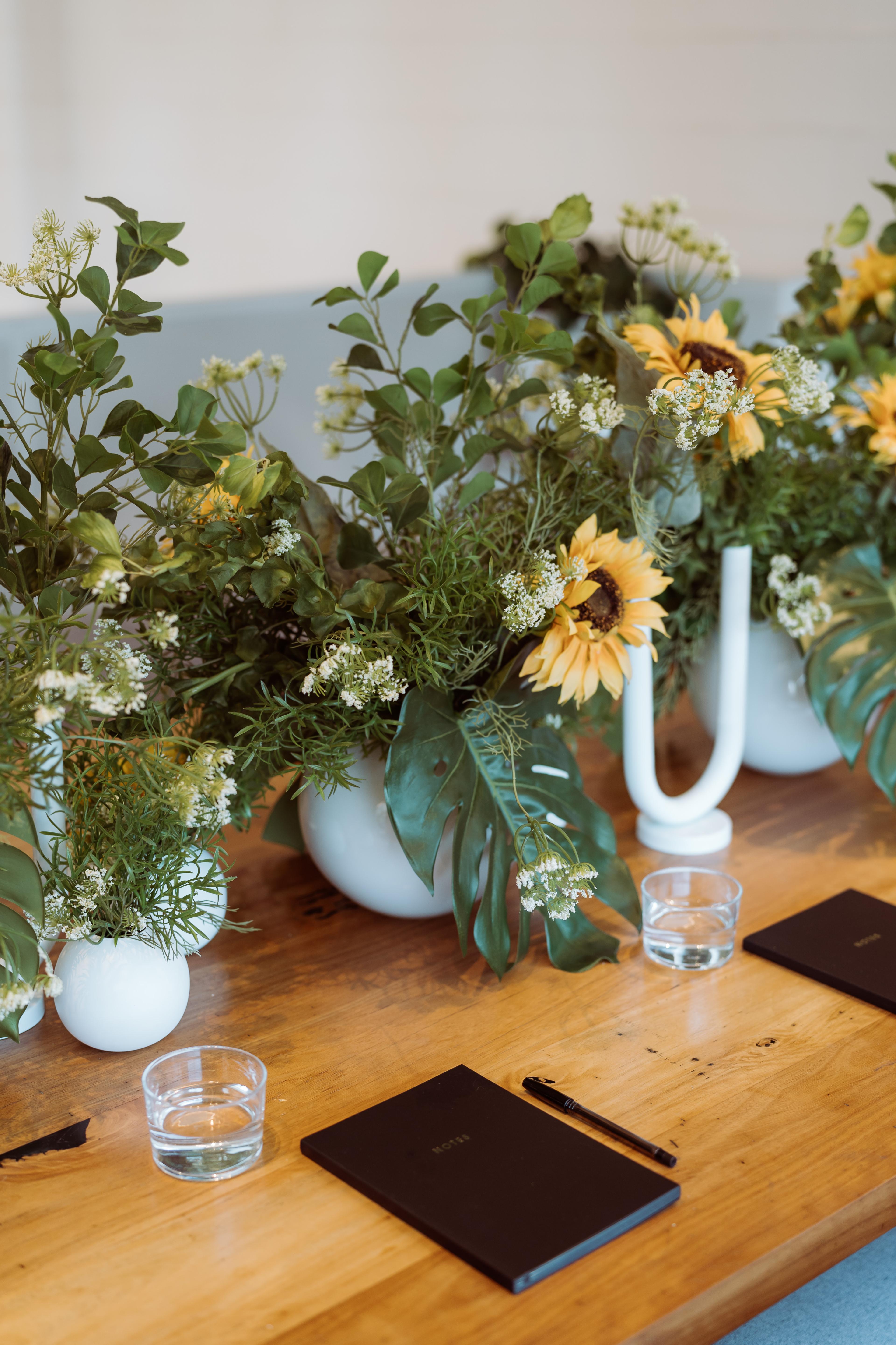 Floral table styling for the Industry Beans Newstead brand activation, featuring white vessels, sunflowers, greenery and timber table details.