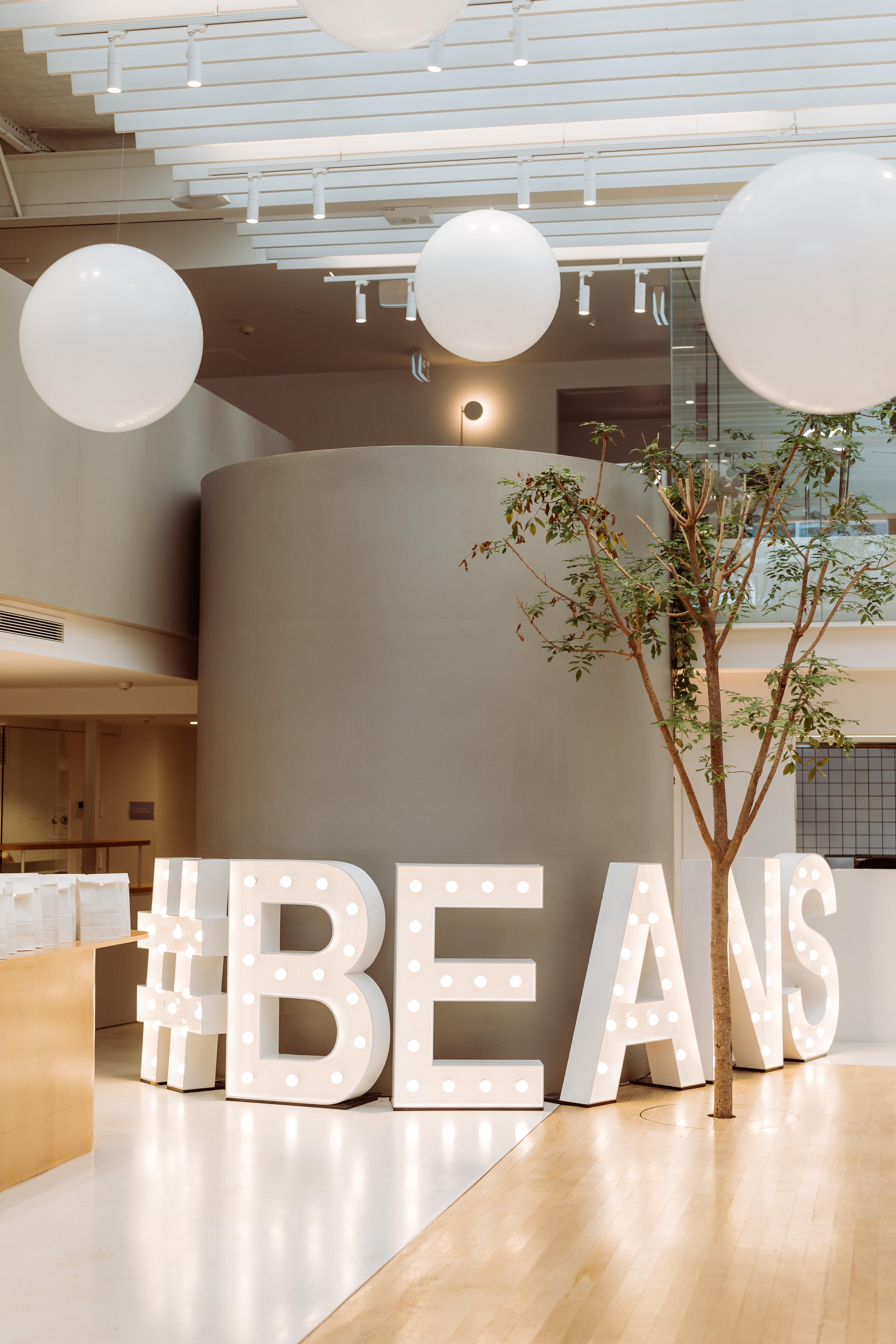 Illuminated Beans light up event letters inside the Newstead Brisbane venue, styled with oversized white balloons for a modern brand activation.