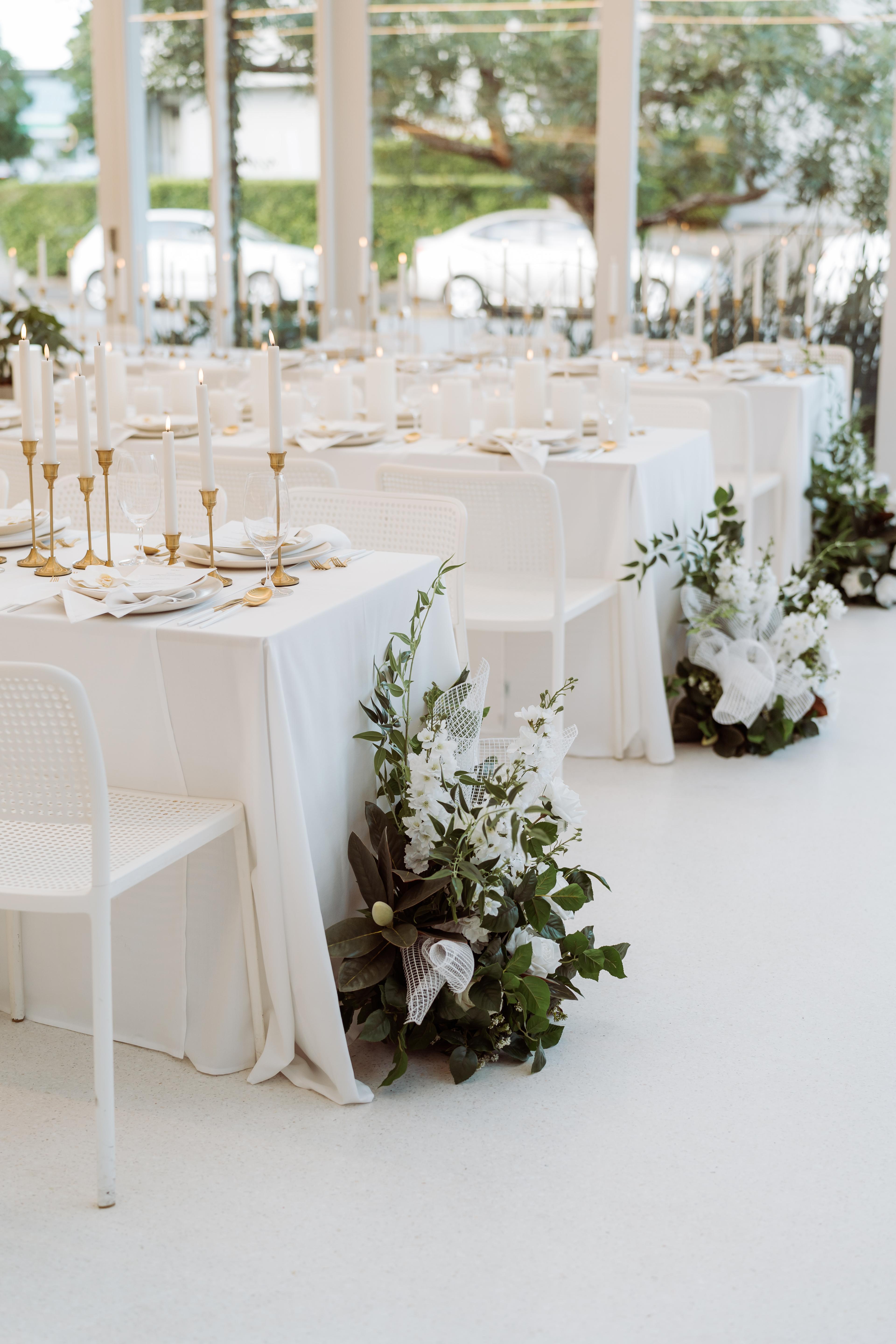 White event tables styled for the Industry Beans Newstead brand activation in Brisbane, featuring candlelight, white florals and greenery.