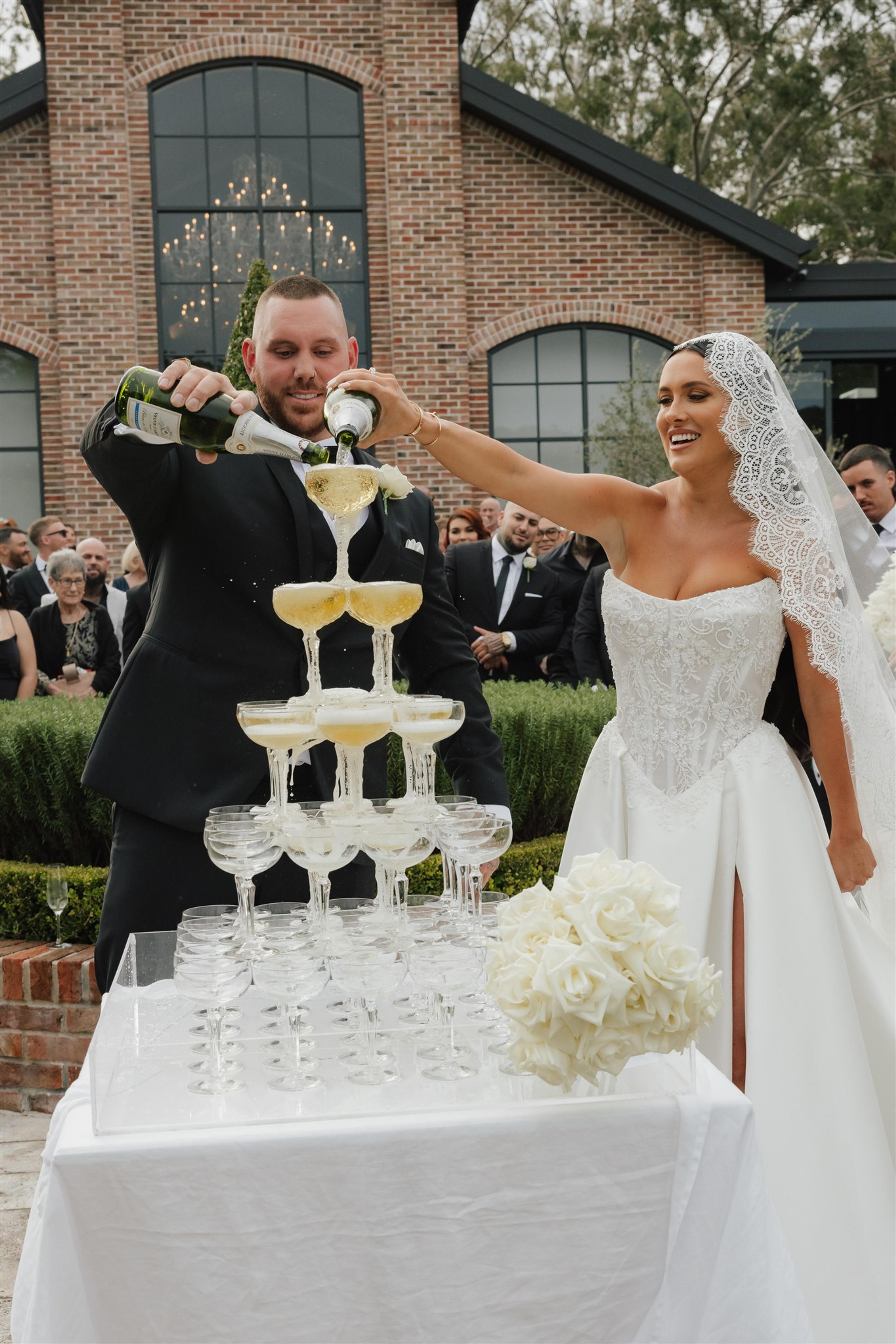 Rochelle and Jeff pouring champagne over a champagne tower after their wedding ceremony at The Valley Estate Gold Coast.