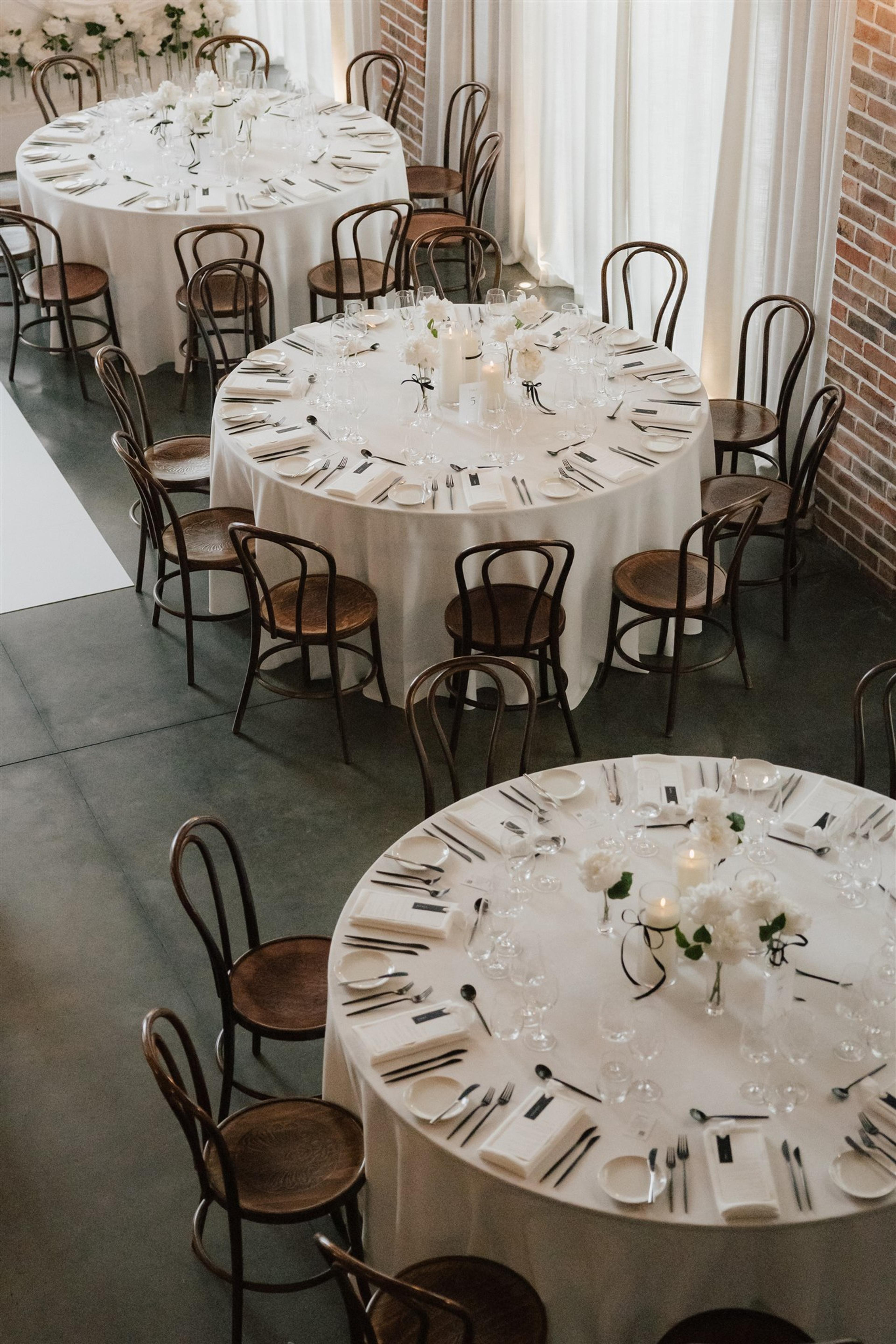 Reception styling at The Valley Estate Gold Coast with round tables, white florals, black bentwood chairs and a long bridal table.