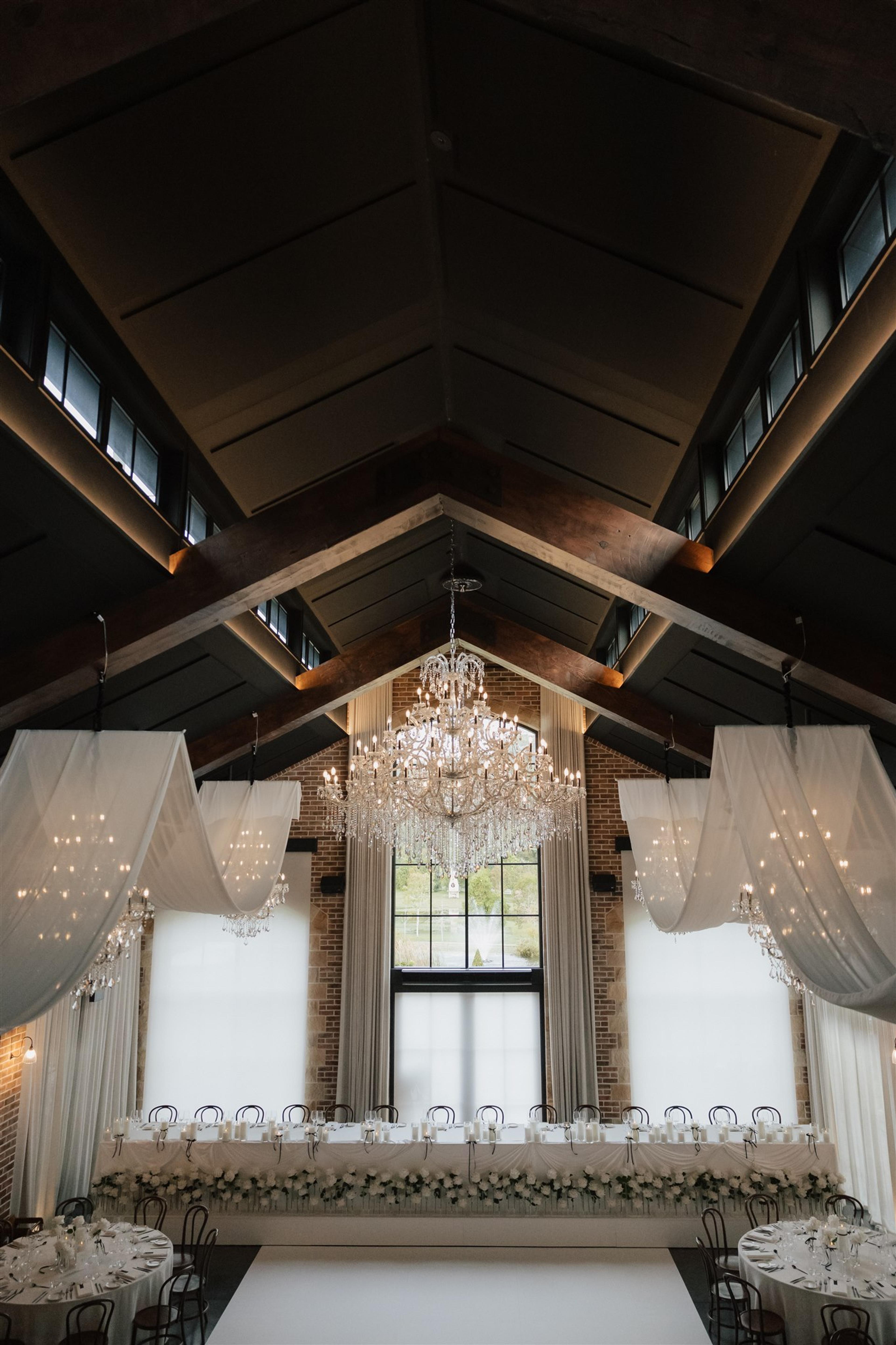 Overhead view of round wedding reception tables with white linen, black cutlery and candlelit floral styling at The Valley Estate Gold Coast.
