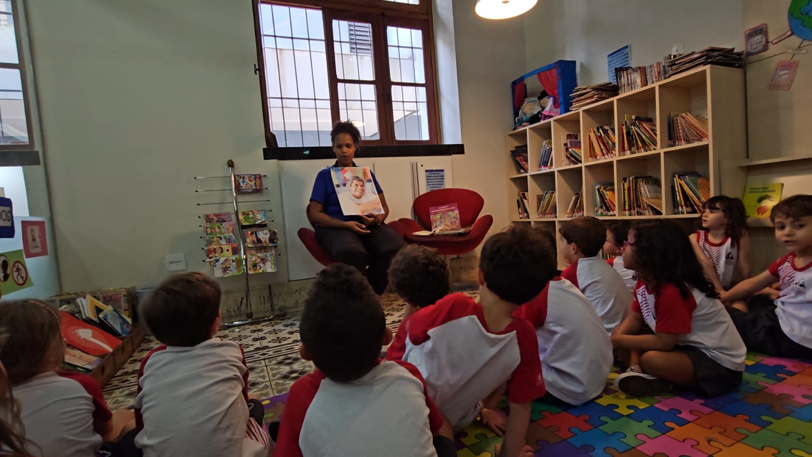 Bibliotecária apresenta um livro de Jonas Ribeiro a crianças da Educação Infantil