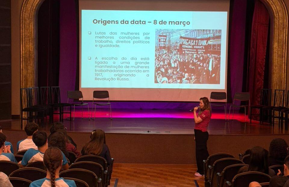 Professora apresenta a origem do Dia Internacional da Mulher a estudantes no teatro