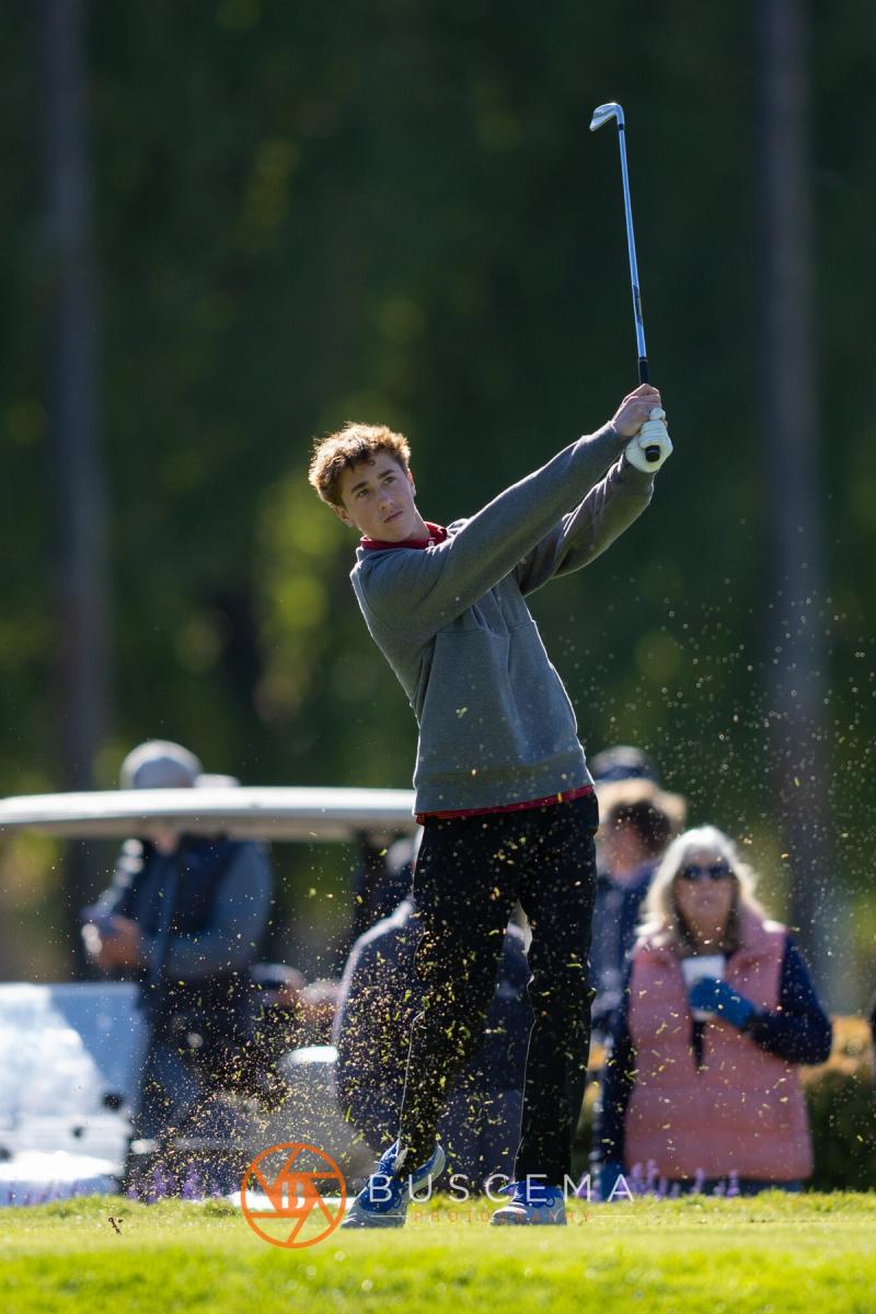 Boys golfer driving off the tee with grass flying at the 6A state golf championships at Avondale Golf Club