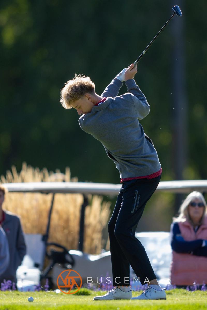 Boys golfer finishing his swing on the first tee at the 6A state golf championships at Avondale Golf Club