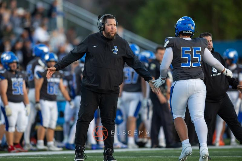 A Coeur d'Alene coach directing a player on the sideline during the home opener