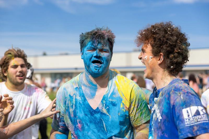 Coeur d'Alene senior covered in blue color powder laughing with a friend