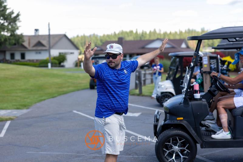 A golfer in Viking blue throwing his arms up in celebration in the cart lot