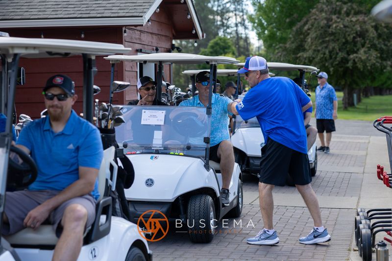 Golfers in carts as a volunteer in Viking blue walks the cart line