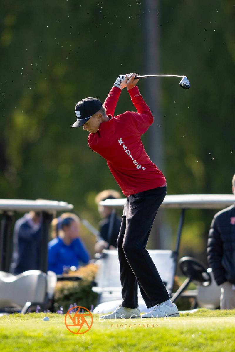 Boys golfer in a red jacket at the top of his backswing on the tee at the 6A state golf championships at Avondale Golf Club