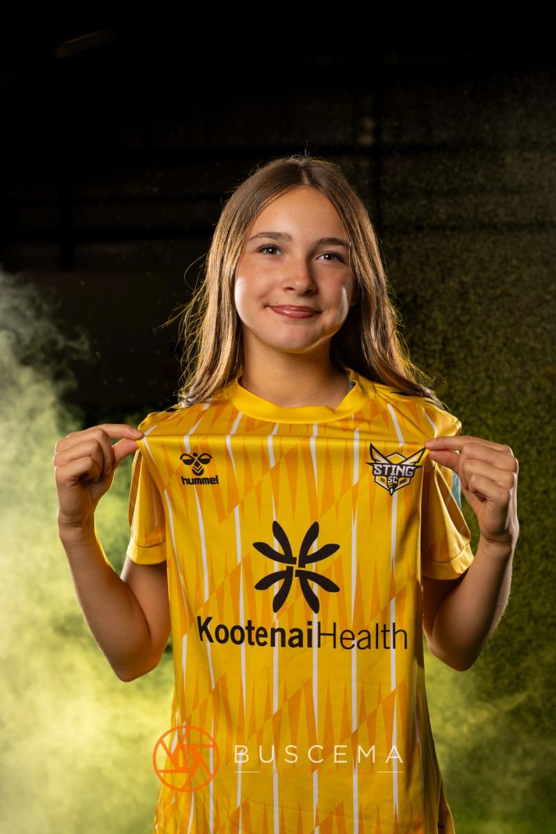 Smiling Sting 13G Academy player holding out her jersey