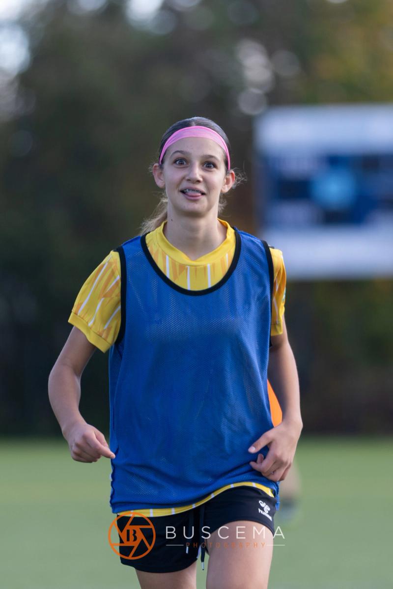 Smiling Sting 13G Academy player in a blue pinnie on the sideline