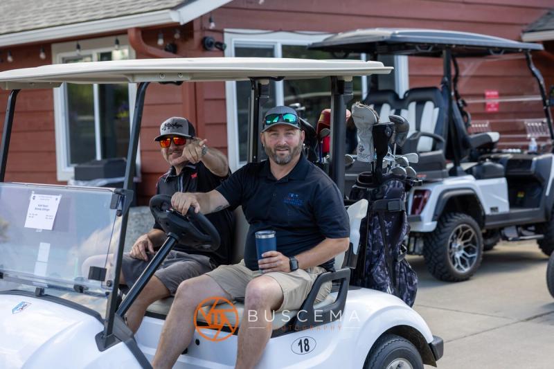 Two golfers in cart 18 smiling at the camera