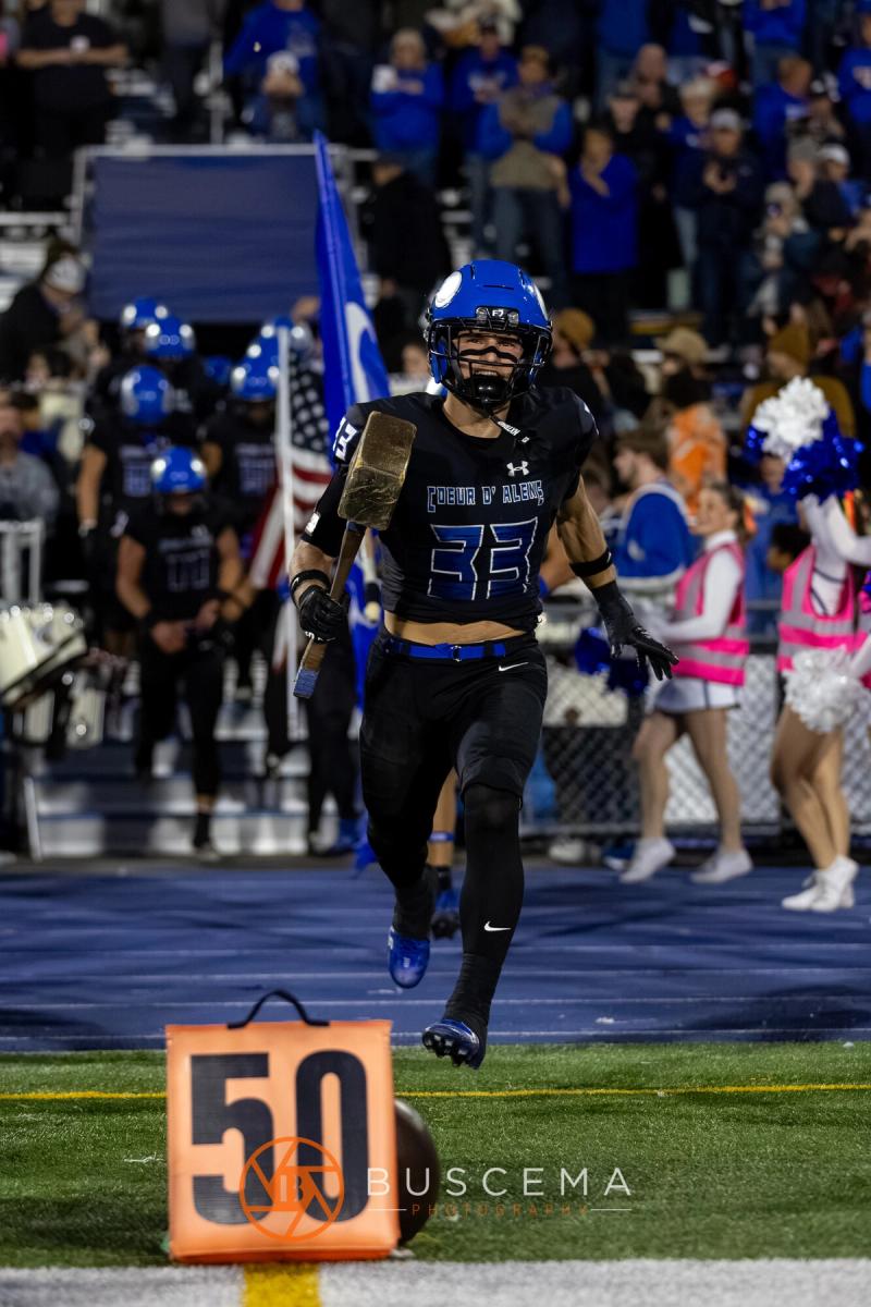 A Coeur d'Alene player carries the team flag onto Viking Field ahead of kickoff