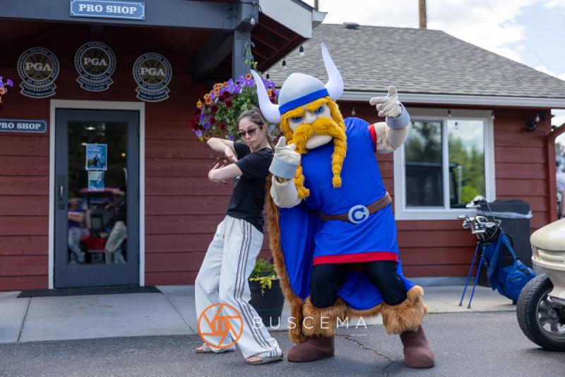 A golfer and the Viking mascot posing together outside the pro shop