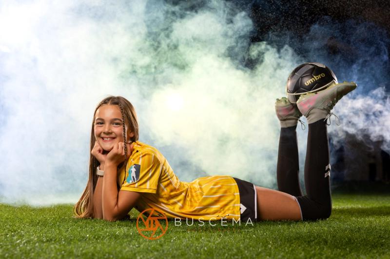 Sting 13G Academy player lying on the turf with a ball balanced on her feet
