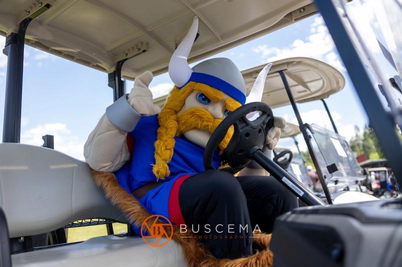 The Viking mascot giving a thumbs up from the driver's seat of a golf cart