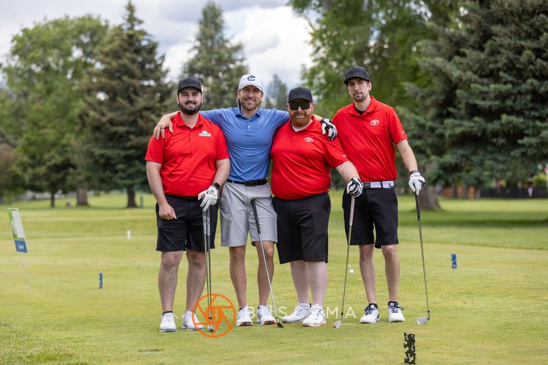 A foursome in red and blue posing arm in arm on the tee