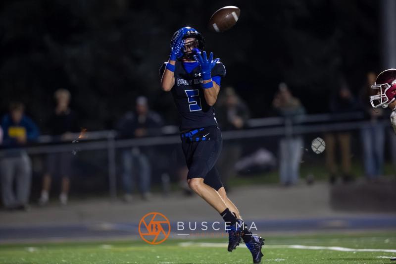 A Coeur d'Alene receiver leaps for the ball under the lights