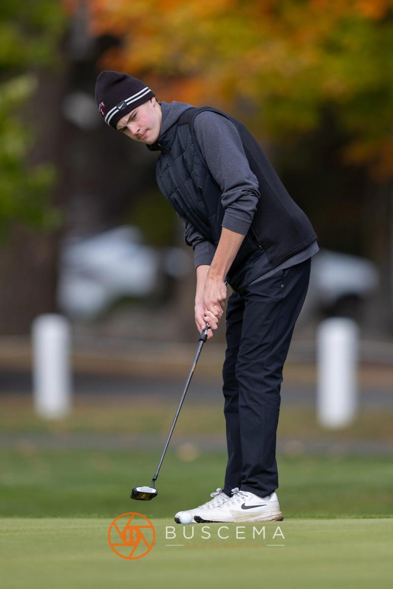 Golfer in a beanie lining up a putt at the 6A state golf championships at Avondale Golf Club