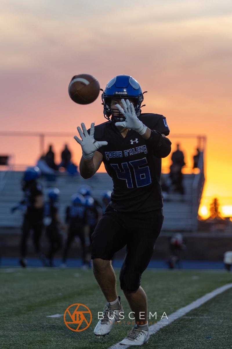 A Coeur d'Alene receiver tracks the ball into his hands against a sunset sky
