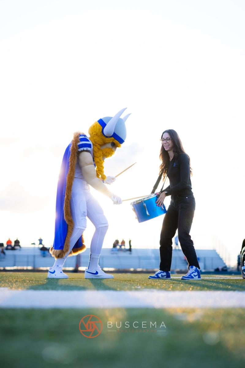 The Coeur d'Alene Viking mascot playing a drum along the sideline at Viking Field
